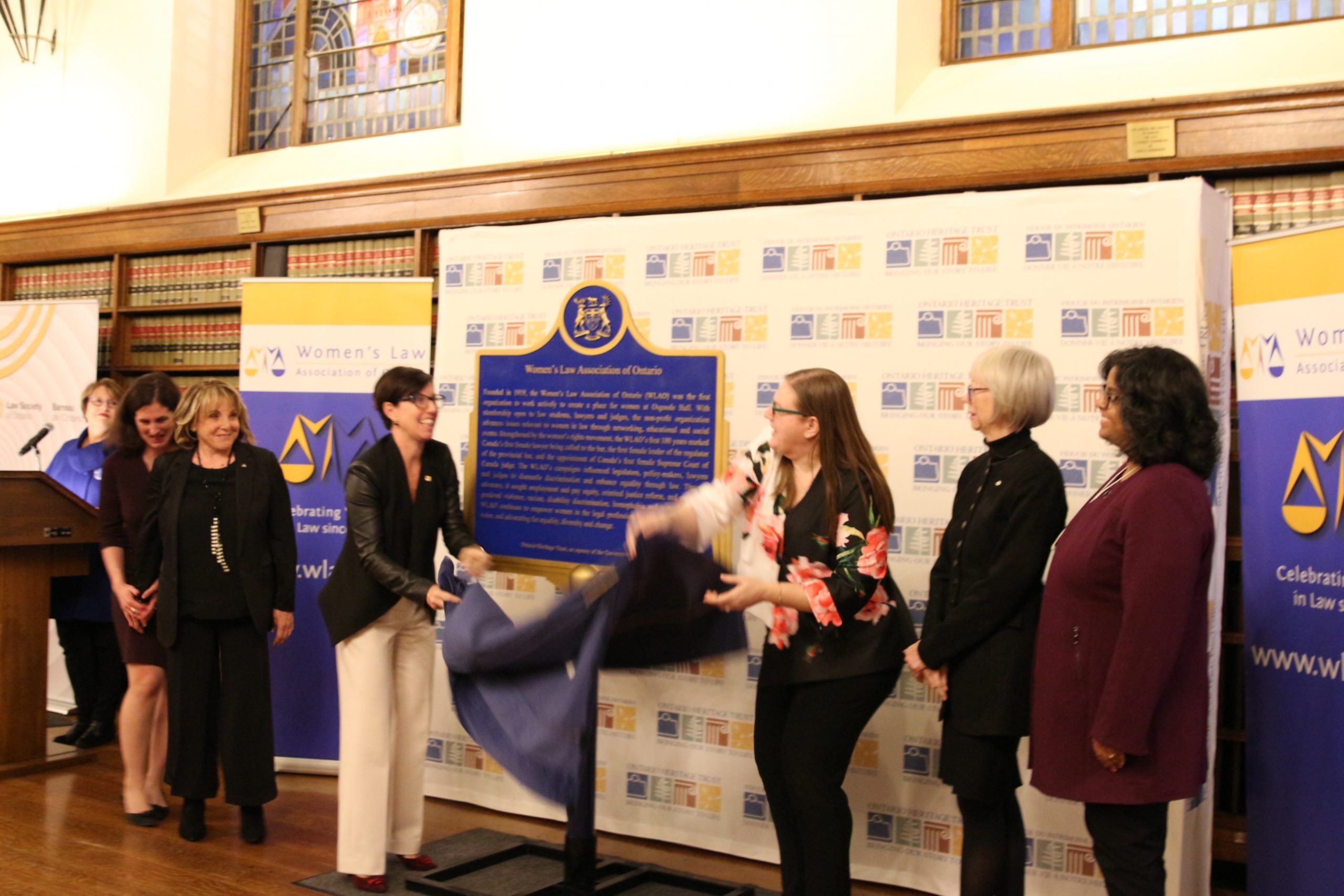 A group of women smiling as a plaque is unveiled to celebrate 100 years of The WLAO.