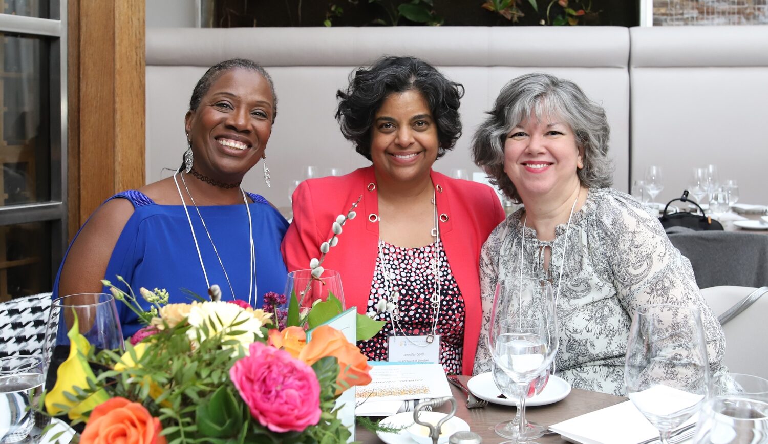 Three members of The WLAO smiling as they pose for a picture over a meal together.