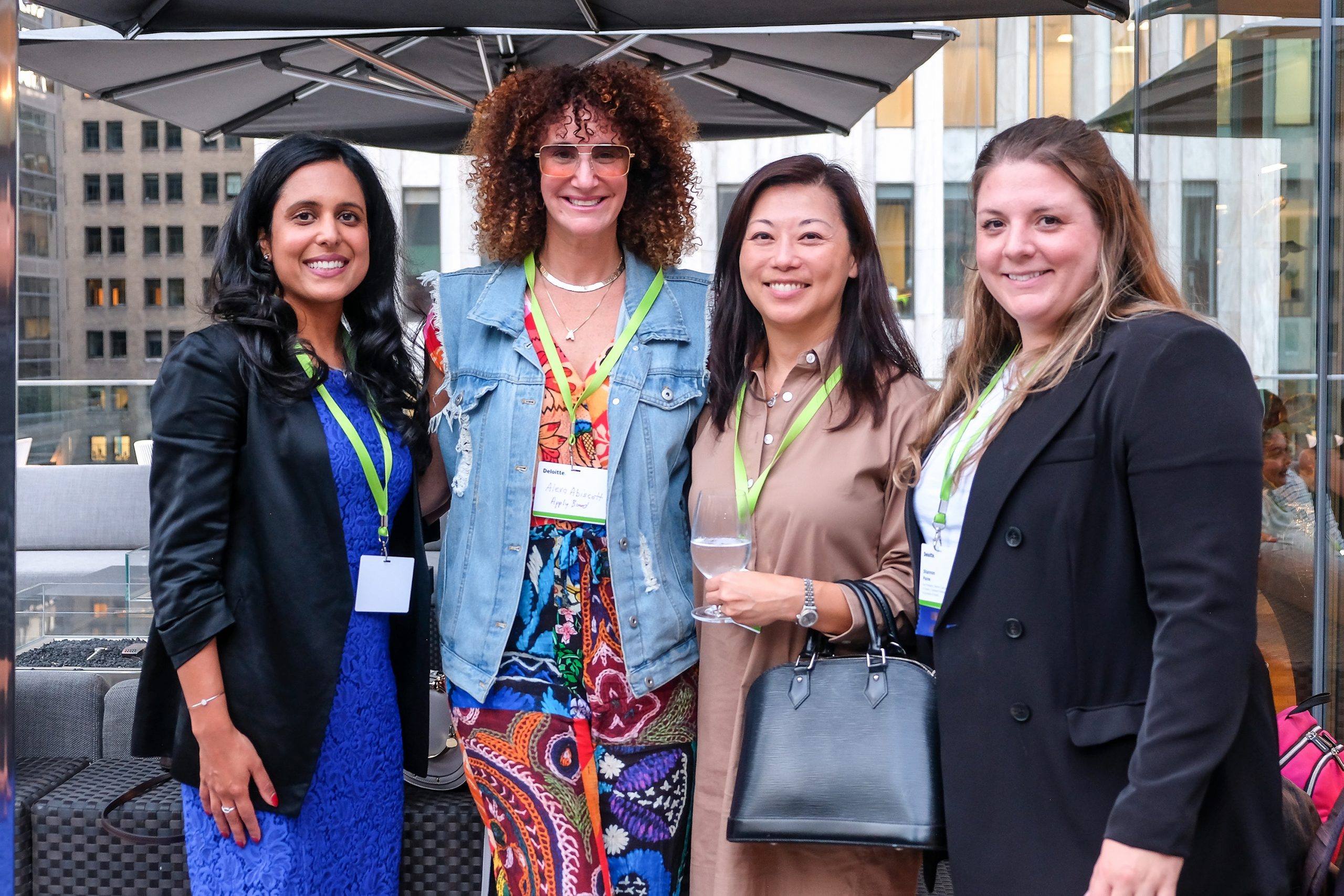 Four members of the WLAO posing for a picture as they smile and enjoy beverages at a networking event.