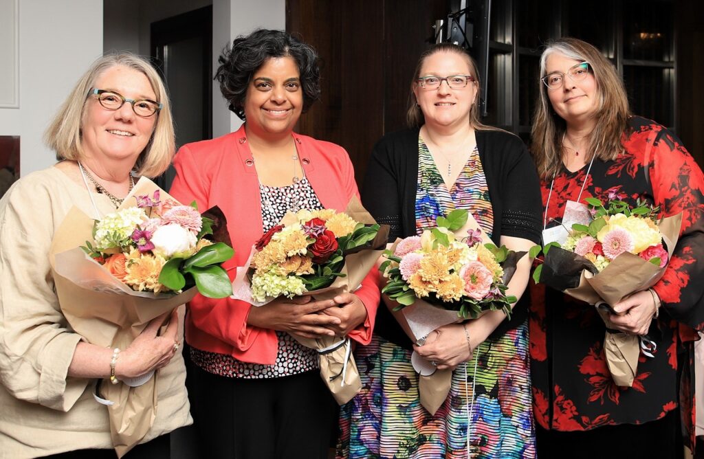 Four women carrying bouquets of flowers.
